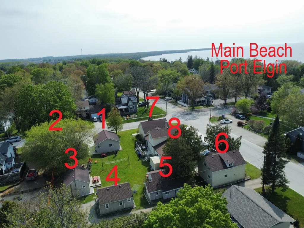 Aerial view of Starlight Cottages showing all 8 numbered cottages with Lake Huron and Port Elgin Main Beach in the background